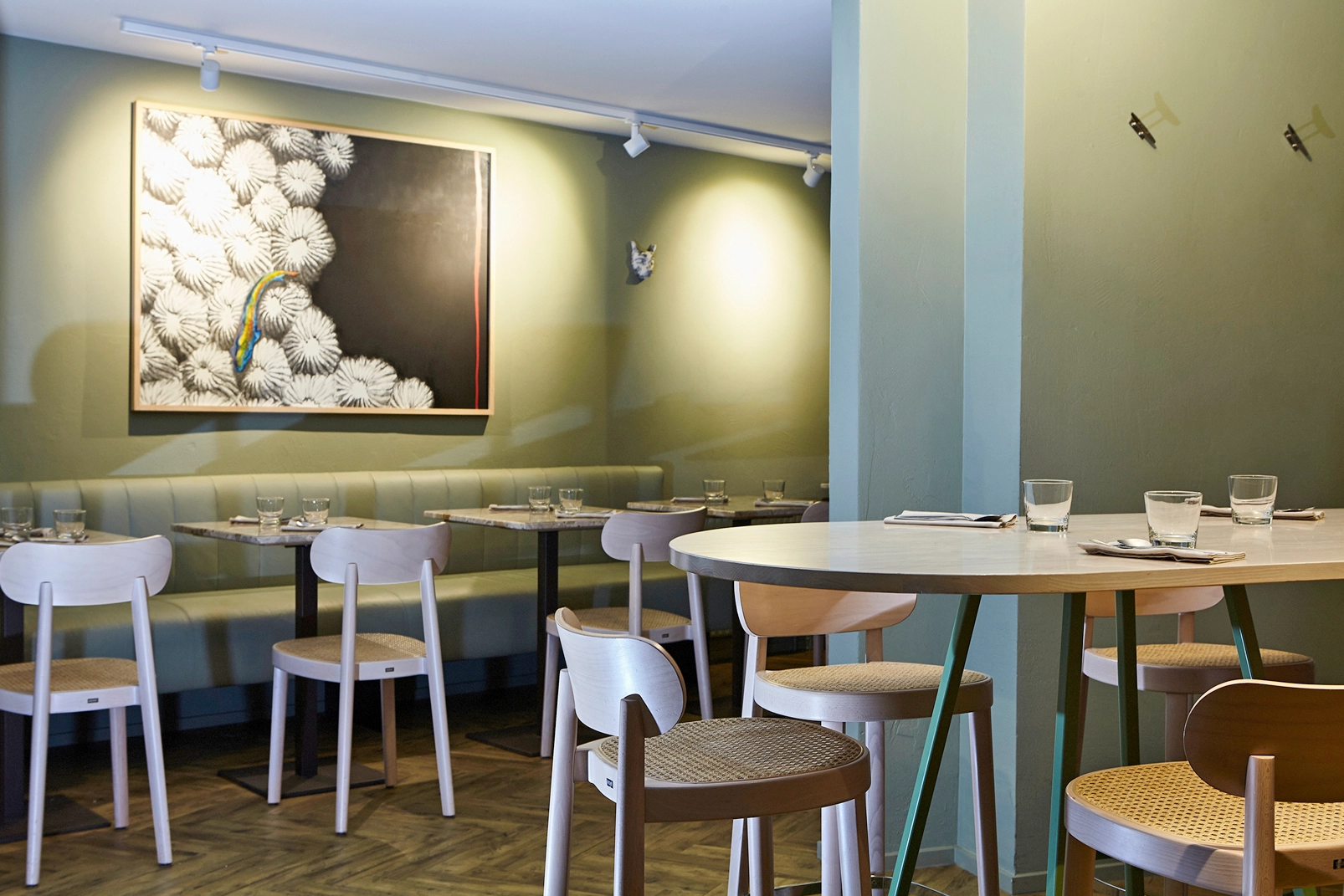 Gastraum mit lindgrünen Wänden und hellem Mobiliar. Interior der Seafoodbar XO.
